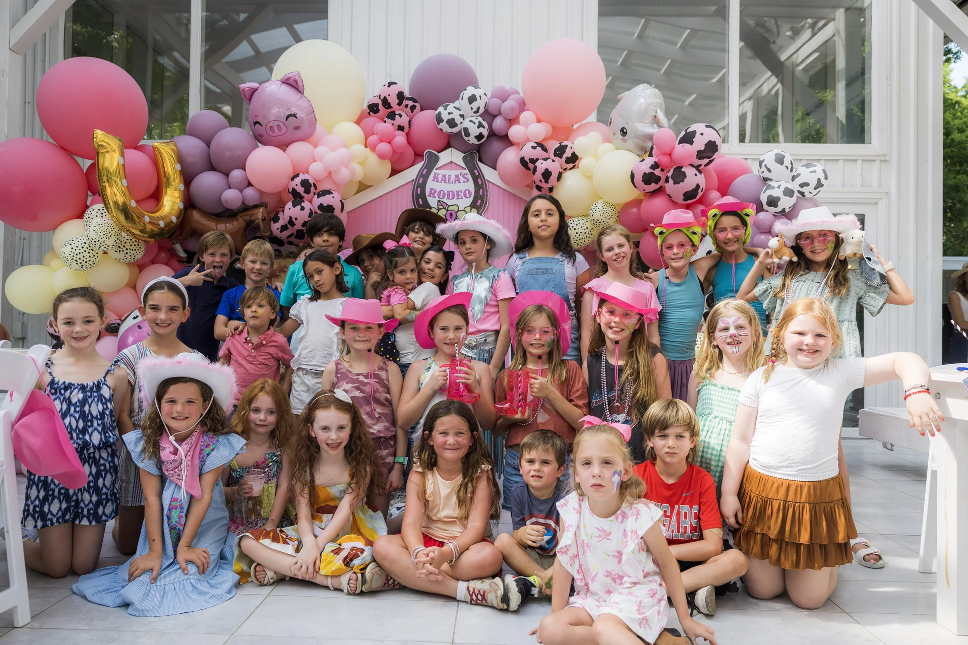Children gathered in front of a pastel balloon installation at a Poppin Kids celebration