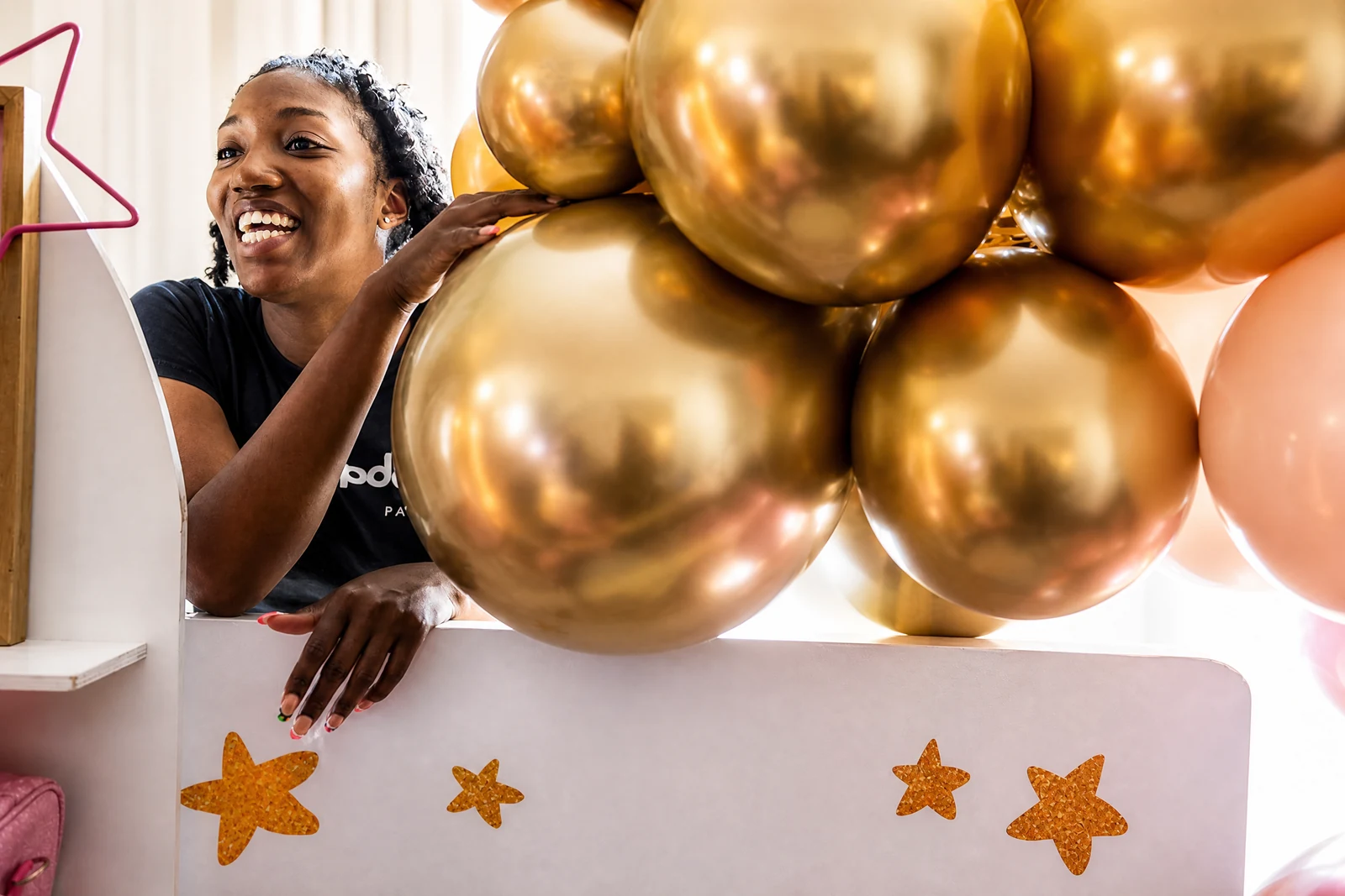 Balloon artist styling an oversized gold balloon installation at a Poppin Kids event