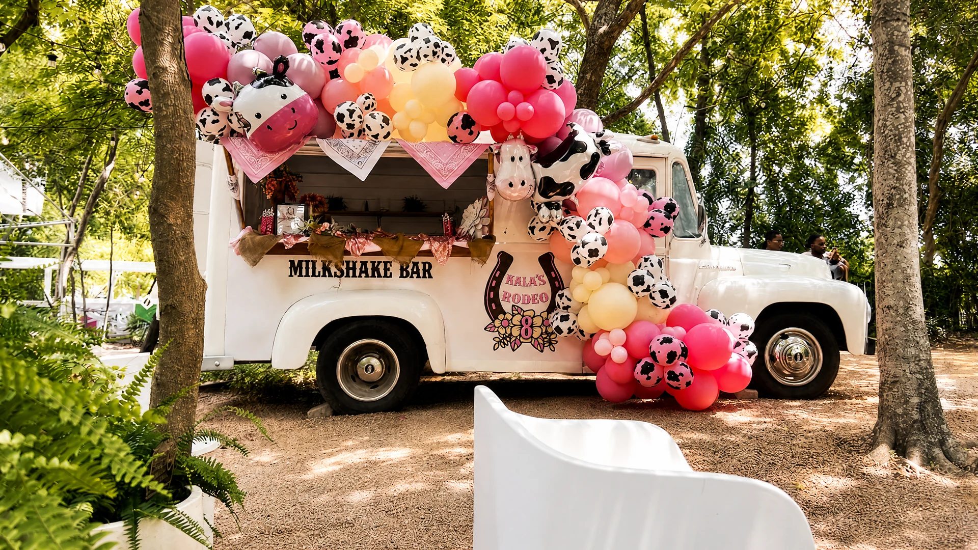 Custom pink milkshake bar truck with cow-print balloons and personalized birthday styling